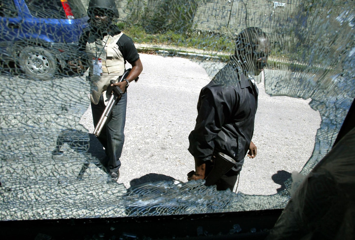 Haitian police are seen through a broken car window 29 February 2004 in Port-au-Prince. Angry mobs rampaged through the Haitian capital after President Jean Bertrand Aristide fled the country, leaving smoke billowing over the city and at least 10 dead.