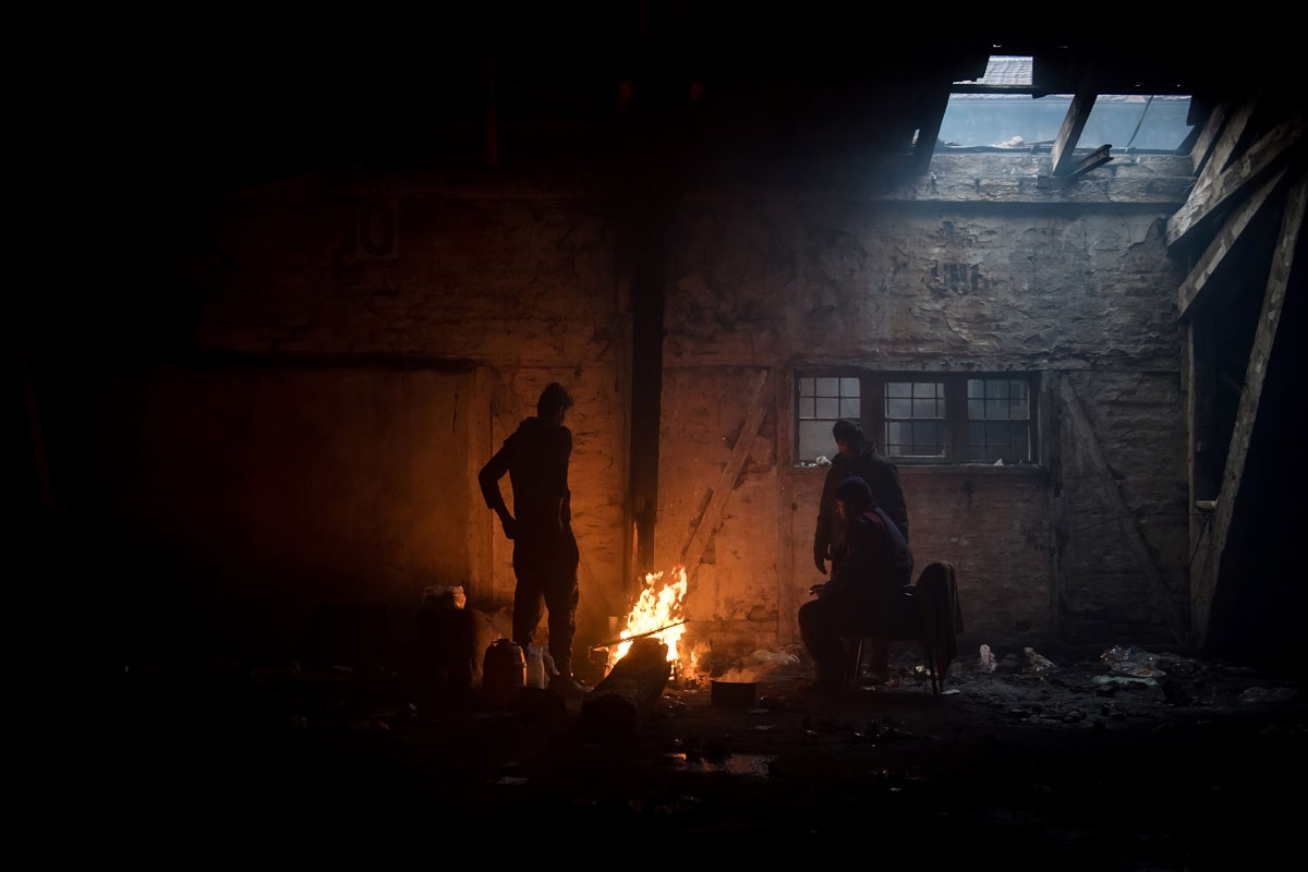 Migrants gather around a bonfire inside of derelict warehouse used as a shelter near Belgrade's main railway station on January 17, 2017, with temperatures bellow zero Celsius. 