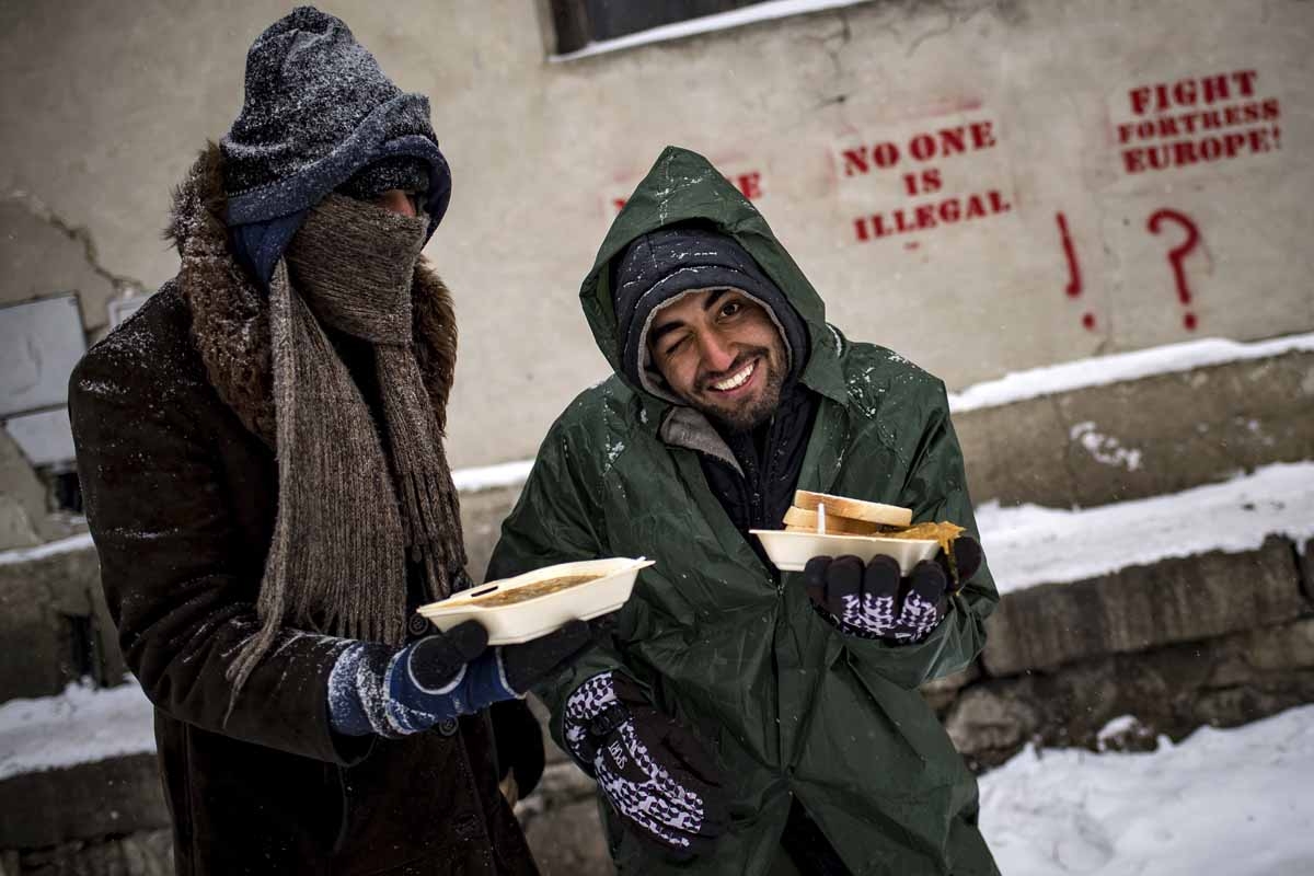 Migrants receive hot meals from volunteers, outside of derelict warehouses which they use as a makeshift shelter, in Belgrade on January 11, 2017, as temperatures dropped to -15 degrees Celsius overnight.