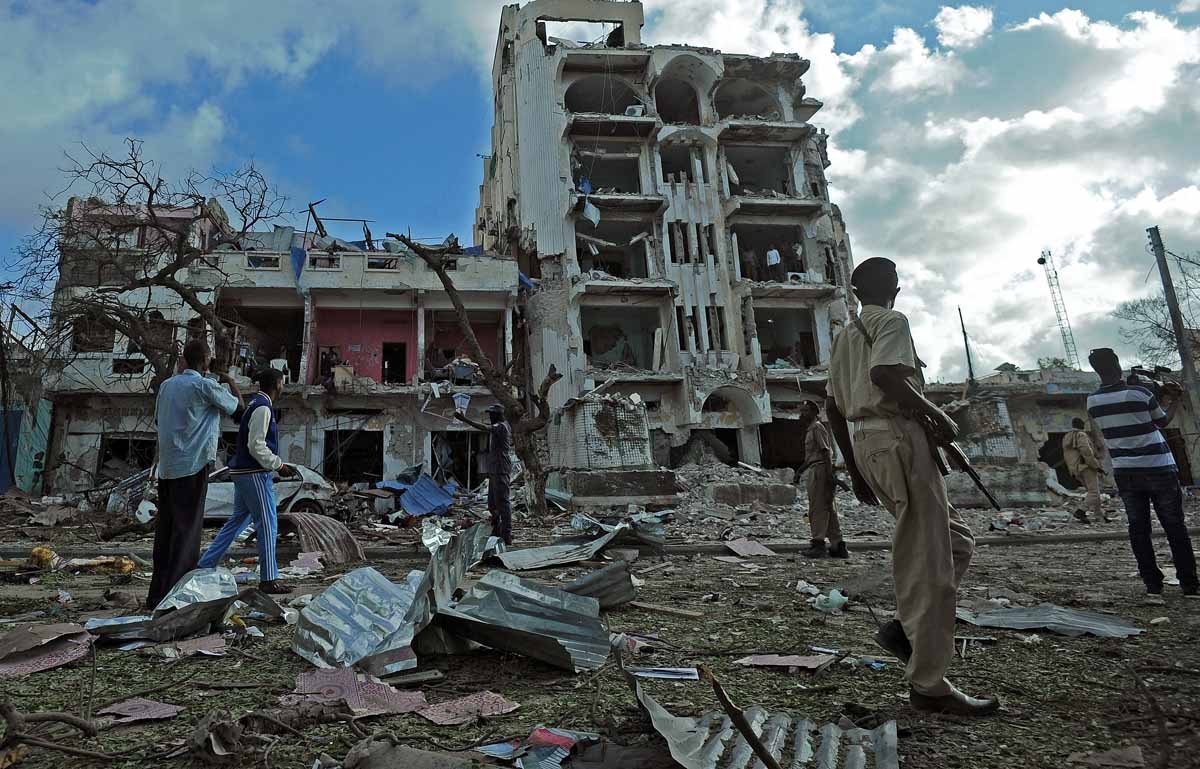 People stand on the scene of a terror attack outside The Ambassador Hotel in Mogadishu on June 2, 2016.