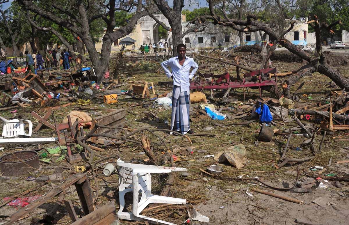 A man stands amongst scattered objects and belongings at the scene of a car bomb attack near the port of the capital Mogadishu, on December 11, 2016.
