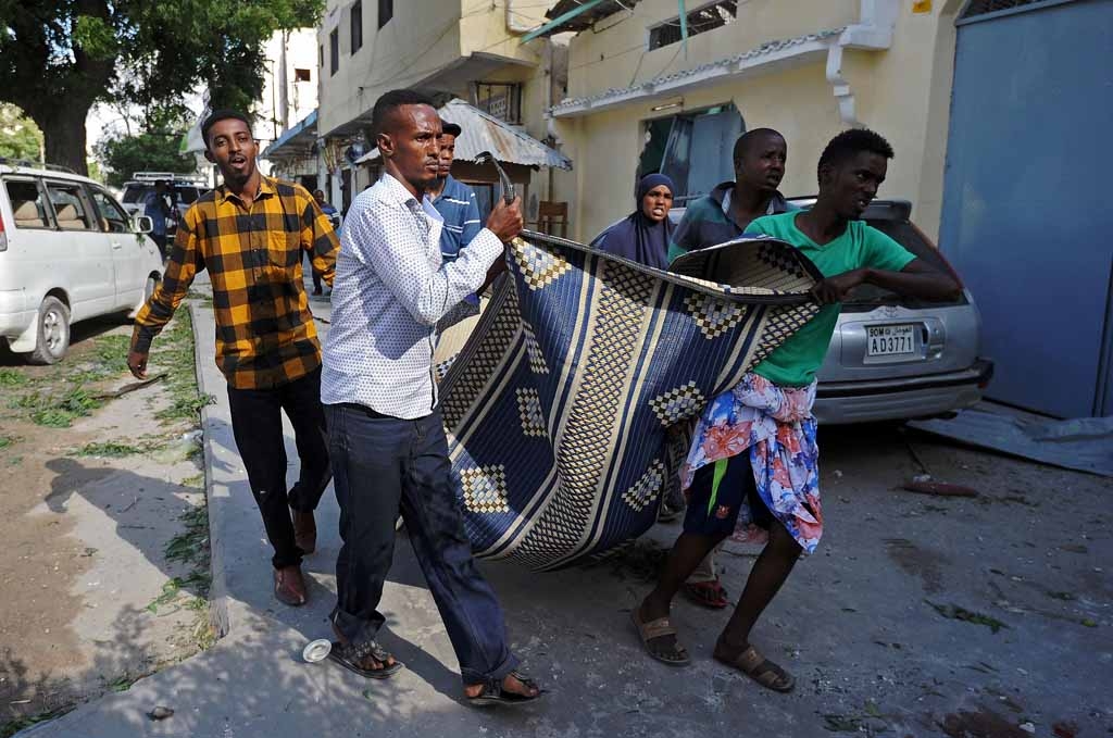 People carry the body of a civilian victim from the scene of a terror attack outside The Ambassador Hotel in Mogadishu on June 2, 2016. People carry the body of a civilian victim from the scene of a terror attack outside The Ambassador Hotel in Mogadishu on June 2, 2016.