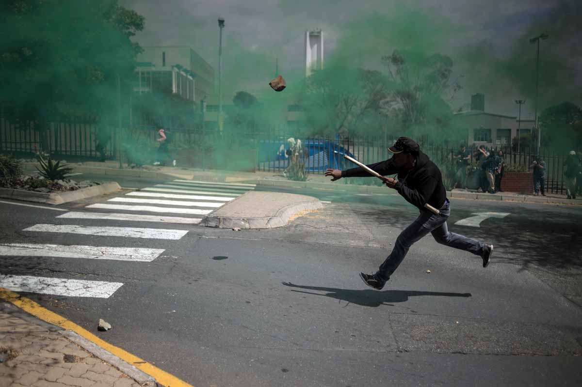 A man throws a stone during a mass protest of the Fees Must Fall movement at the University of Witwatersrand in Johannesburg on October 4, 2016. A man throws a stone during a mass protest of the Fees Must Fall movement at the University of Witwatersrand in Johannesburg on October 4, 2016.