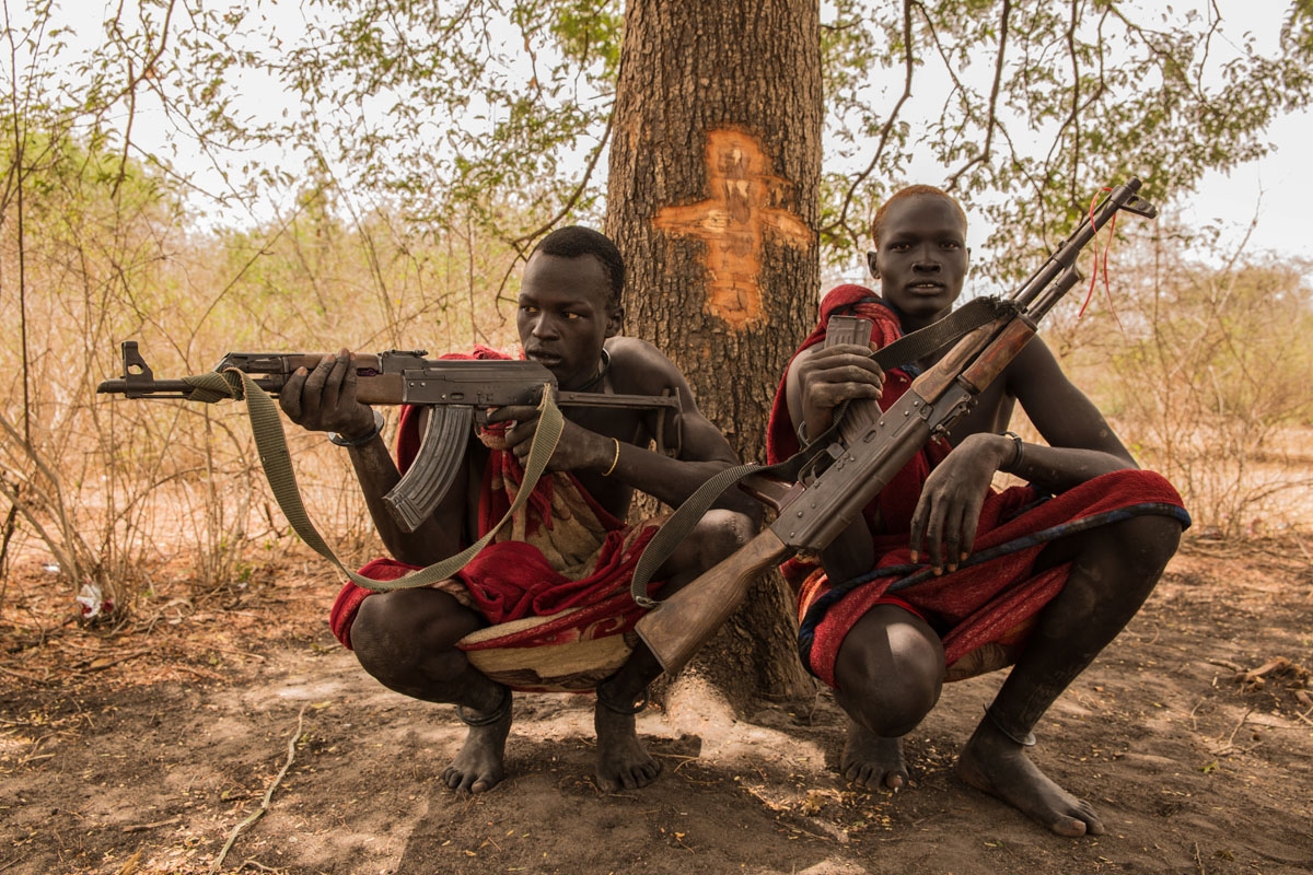 Sudanese cattle keepers from Dinka tribe Makal Maker (R) and Achiek Butich pose with the guns for their protection at their cattle camp in Mingkaman, Lakes State, South Sudan, on March 2, 2018.