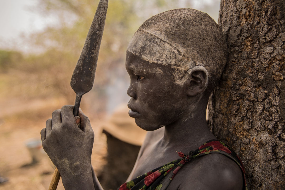 A Sudanese boy from Dinka tribe holds his spear at their cattle camp in Mingkaman, Lakes State, South Sudan on March 3, 2018.