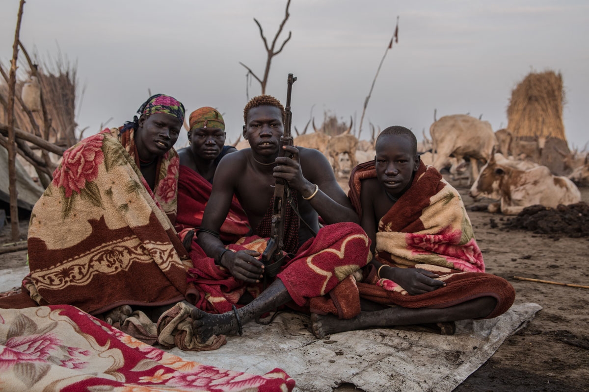 Sudanese men from Dinka tribe pose with a rifle in the early morning at their cattle camp in Mingkaman, Lakes State, South Sudan on March 4, 2018.