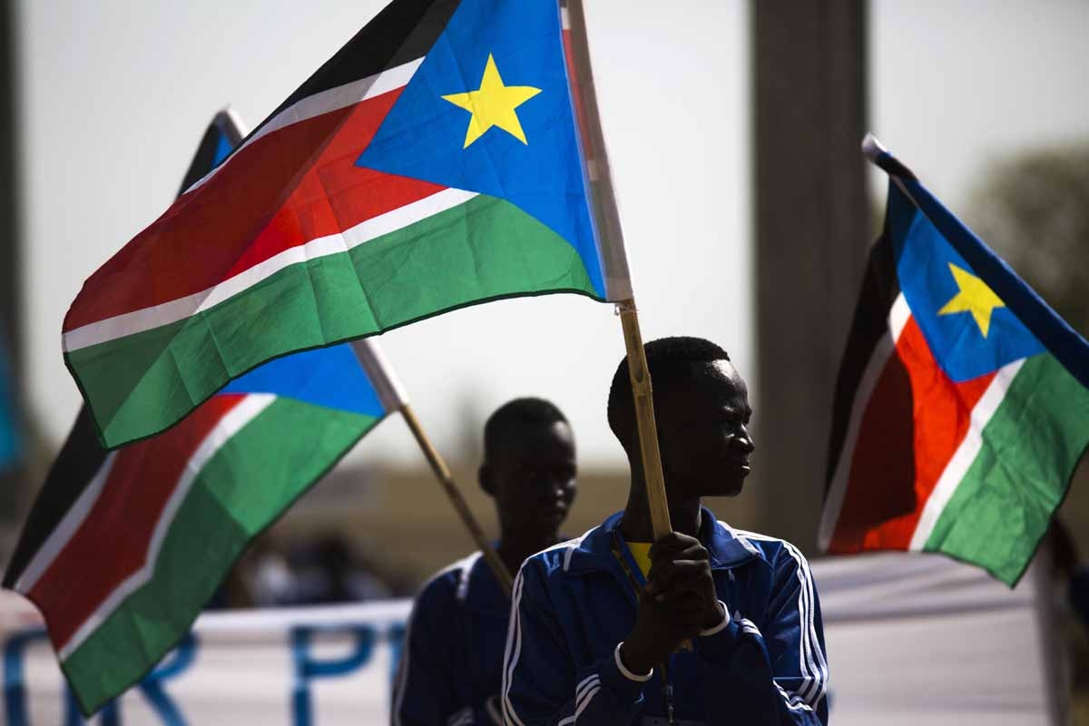 Football players holding South Sudanese flags march at the Juba Stadium, as part of the closing ceremony of the National Unity Day events in Juba, South Sudan, on January 23, 2016.