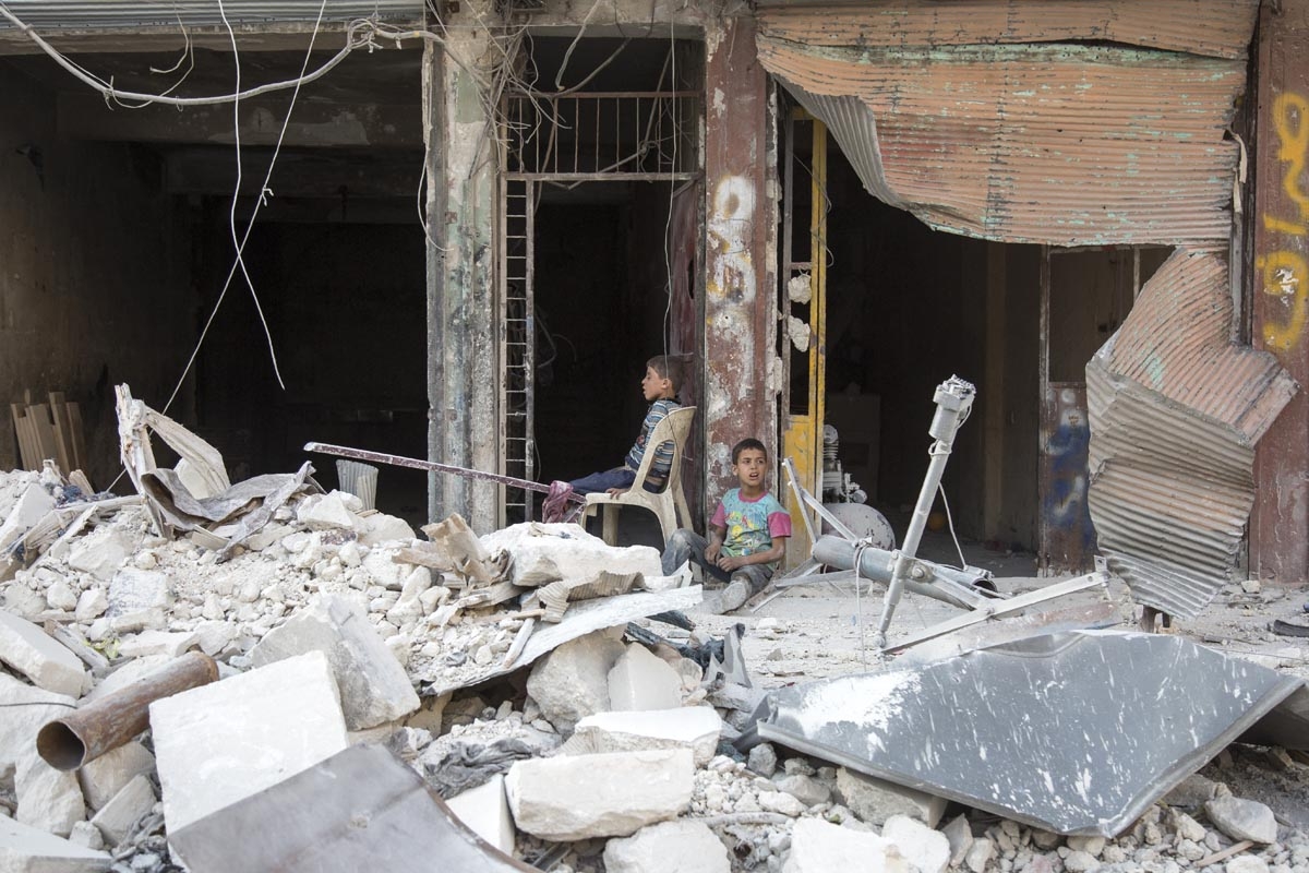 Syrian children sit amidst the rubble of destroyed buildings on July 6, 2016 in the rebel-held district of Tariq al-Bab of the northern city of Aleppo