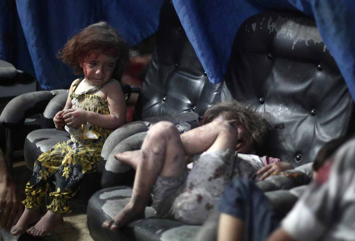 A wounded Syrian child cries looking on at another wounded girl, as they wait for treatment, at a makeshift hospital in the rebel-held town of Douma near Damascus on September 11, 2014, after reported airstrikes by Syrian government forces. 