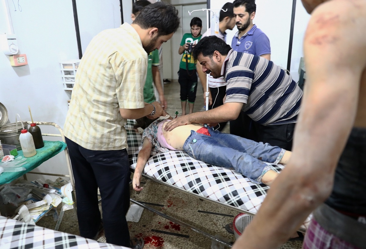 A Syrian man stands next to his daughter as she receives treatment at a makeshift hospital following a reported air stike on the rebel-held town of Douma, east of the capital Damascus, on August 23, 2016. 