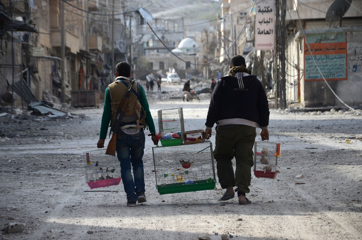 Syrian rebels carry birds in cages in the northwestern border town of al-Bab on February 24, 2017 after Turkish-backed rebels announced the recapture of the town from the Islamic State (IS) group a day earlier. A suicide bomber attacked Turk