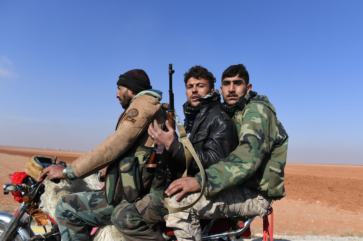 Members of the Syrian government forces drive a motorbike in the village of al-Hajib, near Jabal al-Hass, in the southern part of Aleppo province as they advance with the aim of capturing the Abu Duhur military airport in the ongoing offensive against opp