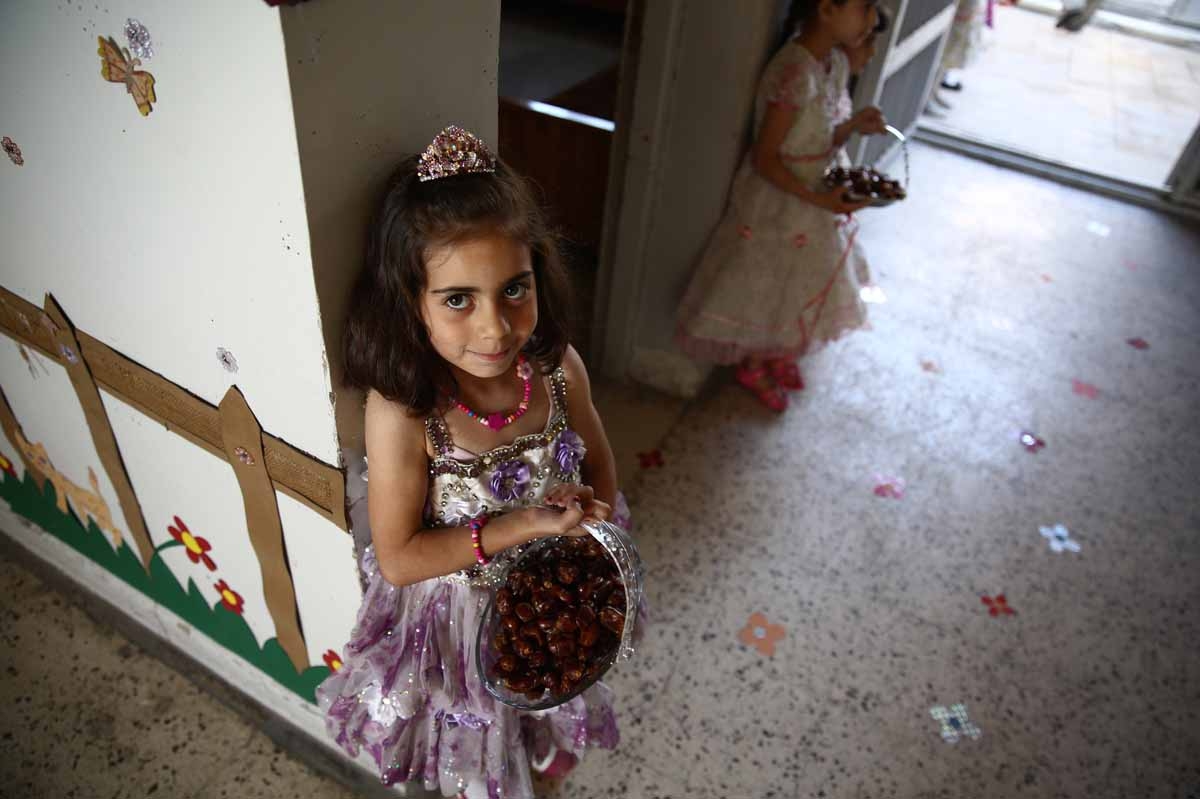 Syrian school girls carry baskets with dates at the entrance of the Saif al-Dawla school as they take part in activities surrounding an art competition organised as part of a local initiative to shift the children's minds from the atrocities of the Syrian