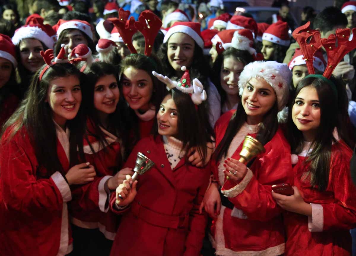 Syrian women dressed in Santa Claus outfits pose for a picture during Christmas celebrations in the northeastern Syrian city of Qamishli on December 24, 2015.