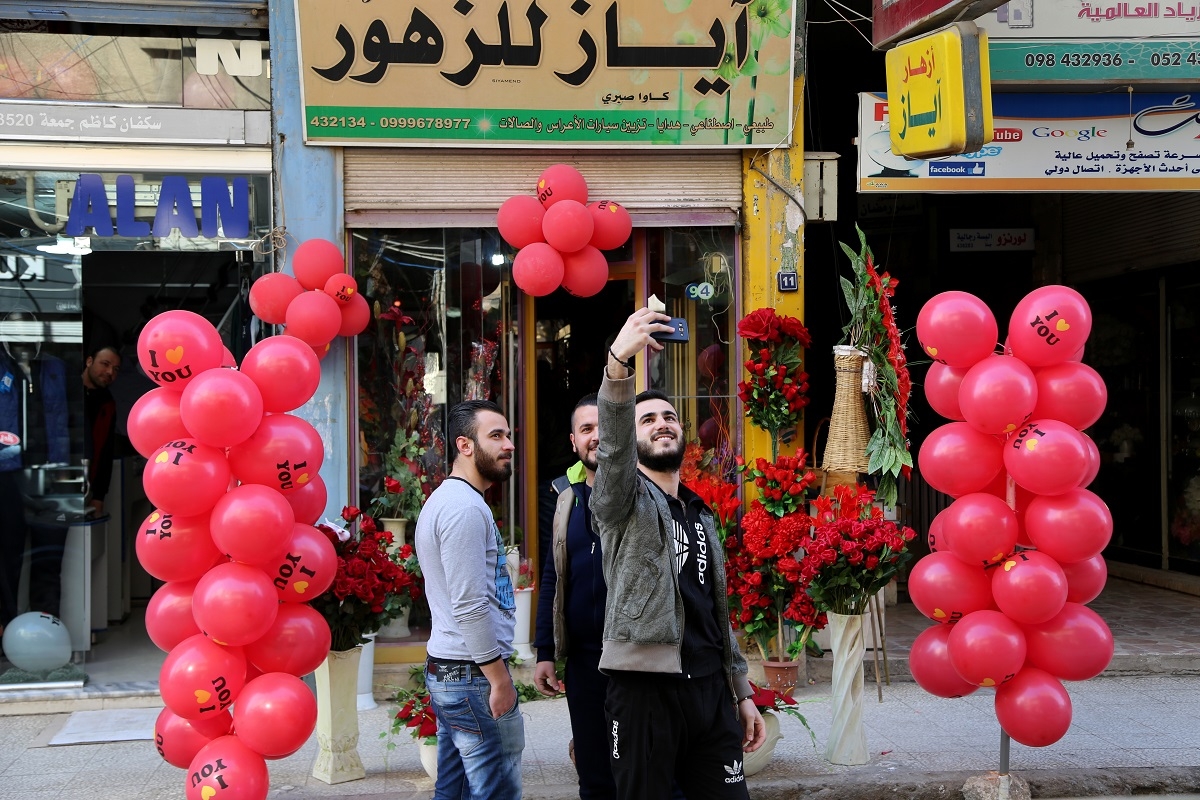 Syrian men take a selfie in front of a shop displaying Valentine's day gifts in the northeastern city of Qamishli on February 13, 2016.