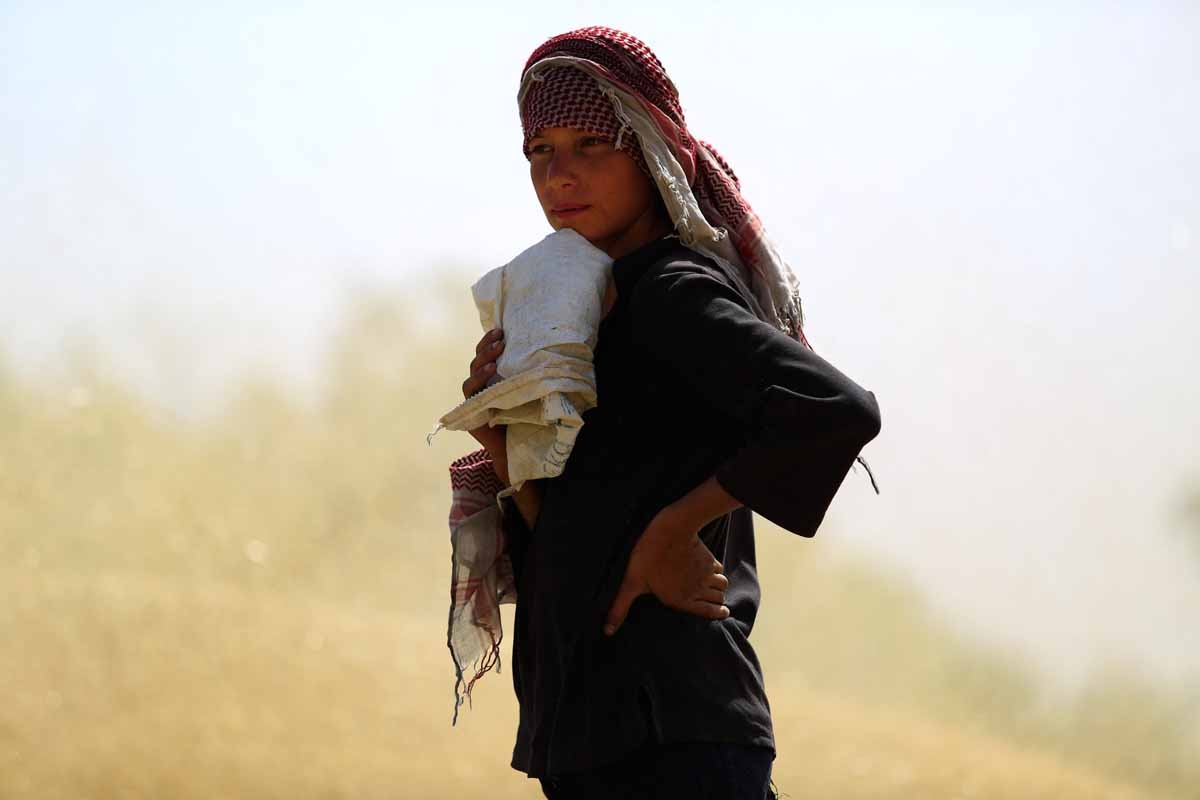 A Syrian young man stands in a wheat field near the rebel-controlled town of Hamouria, in the eastern Ghouta region on the outskirts of the capital Damascus, on June 5, 2016.