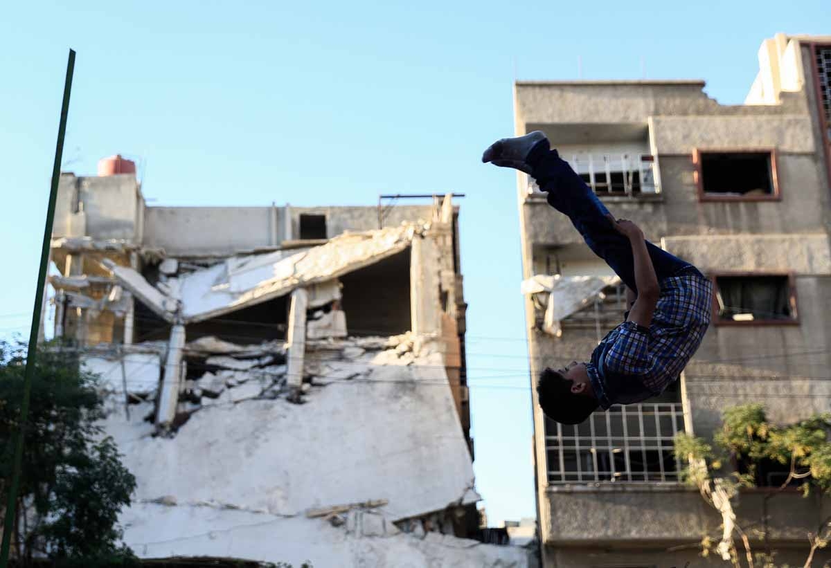 A Syrian boy jumps as he plays in the rebel-held town of Douma, on the eastern edges of the capital Damascus, on the second day of Eid al-Adha Muslim holiday on September 13, 2016.