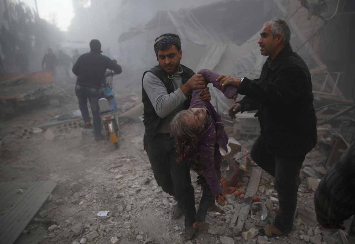 Men evacuate the body of a girl from under the rubble following reported airstrikes on the town of Hamouria in the eastern Ghouta region, a rebel stronghold east of the Syrian capital Damascus, on December 9, 2015.