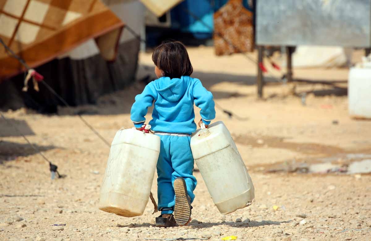 An Iraqi refugee who fled Mosul, the last major Iraqi city under the control of the Islamic State (IS) group, due to the Iraqi government forces offensive to retake the city, carries jerry tanks at the UN-run Al-Hol refugee camp in Syria's Hasakeh provinc