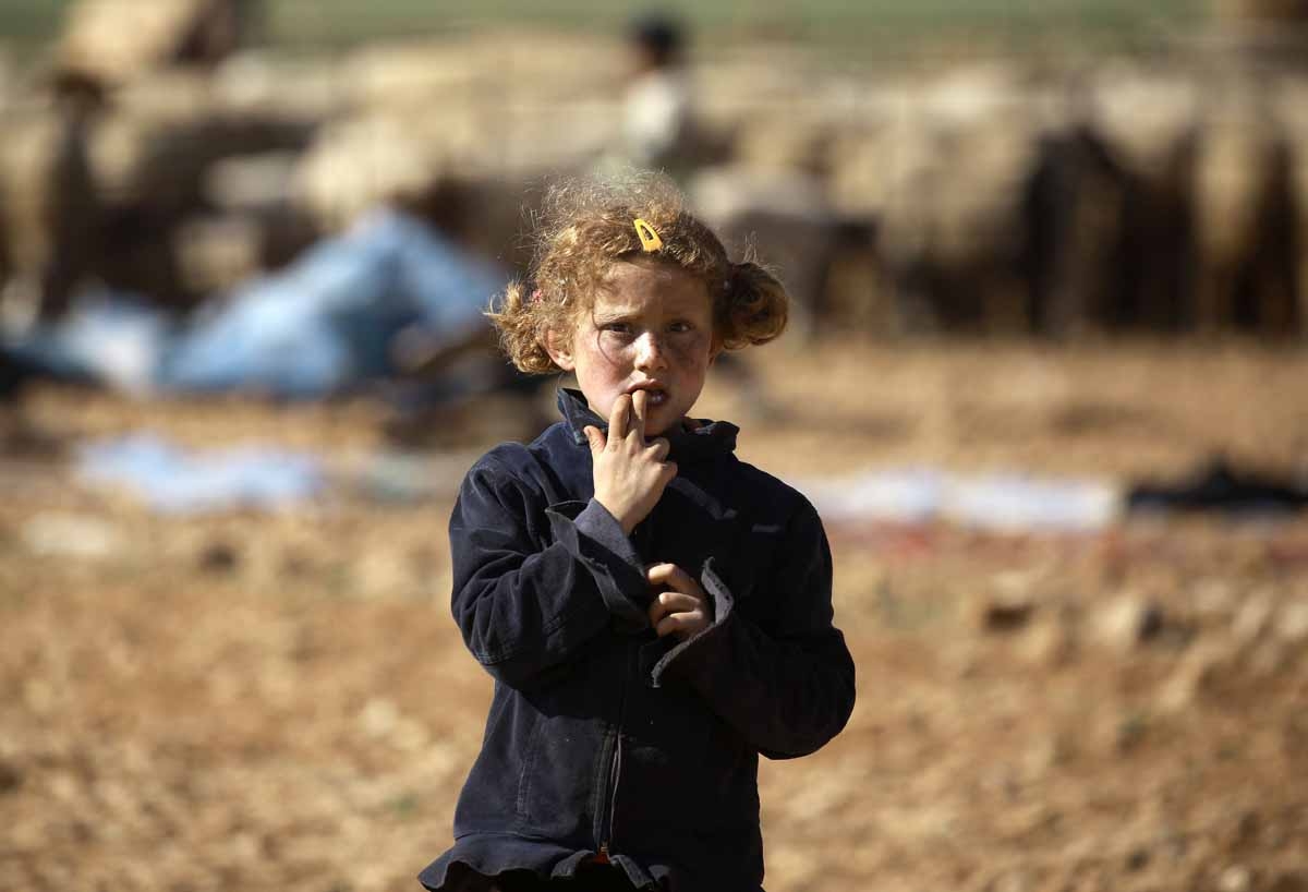 A Syrian child stands at a makeshift camp for displaced people near the town of Manbij on March 6, 2017.