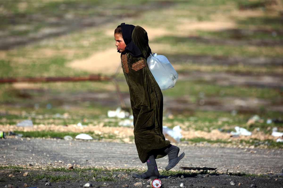 A Syrian girl carries a jug of water at a temporary refugee camp in the village of Ain Issa, housing people who fled Islamic State group's Syrian stronghold Raqa, some 50 kilometres (30 miles) north of the group's de facto capital on March 25, 2017.