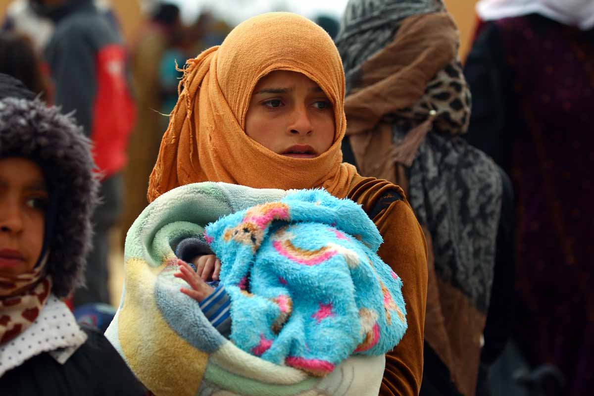 A picture taken on March 30, 2017 shows a displaced Syrian girl carrying a child arriving in the village of Suwaidiya Saghira, north of Tabqa after fleeing home due to the battles between Syrian Democratic Forces and Islamic State (IS) group jihadists.