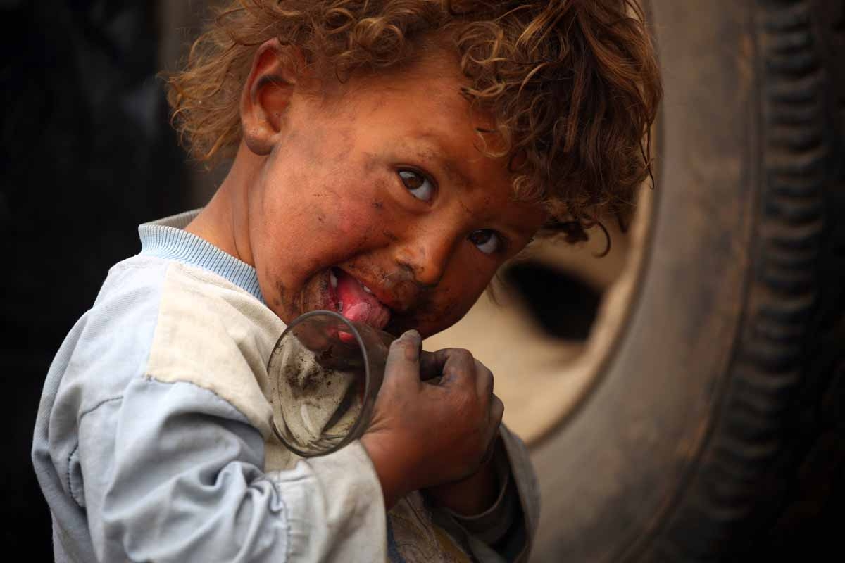 A displaced Syrian child, who fled the countryside surrounding the Islamic State (IS) group stronghold of Raqa, plays with a glass cup at a temporary camp in the village of Ain Issa on April 28, 2017.