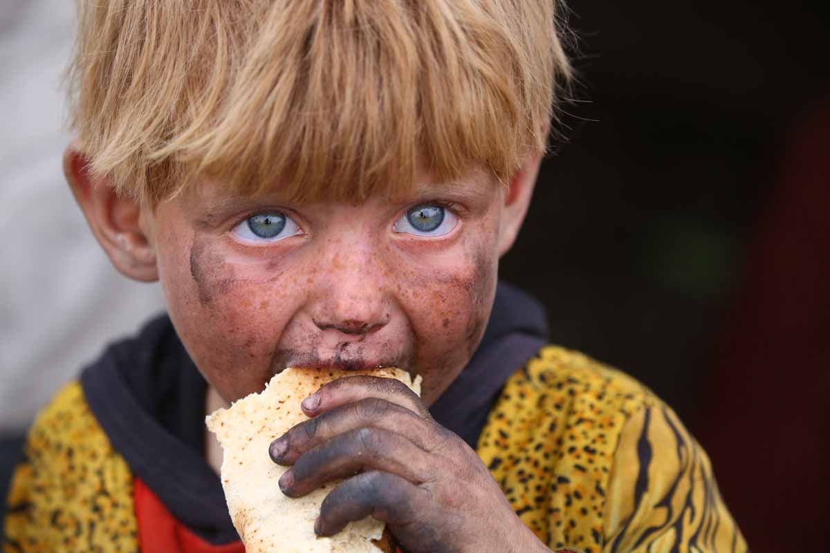 A displaced Syrian child, who fled the countryside surrounding the Islamic State (IS) group stronghold of Raqa, eats at a temporary camp in the village of Ain Issa on May 1, 2017. 