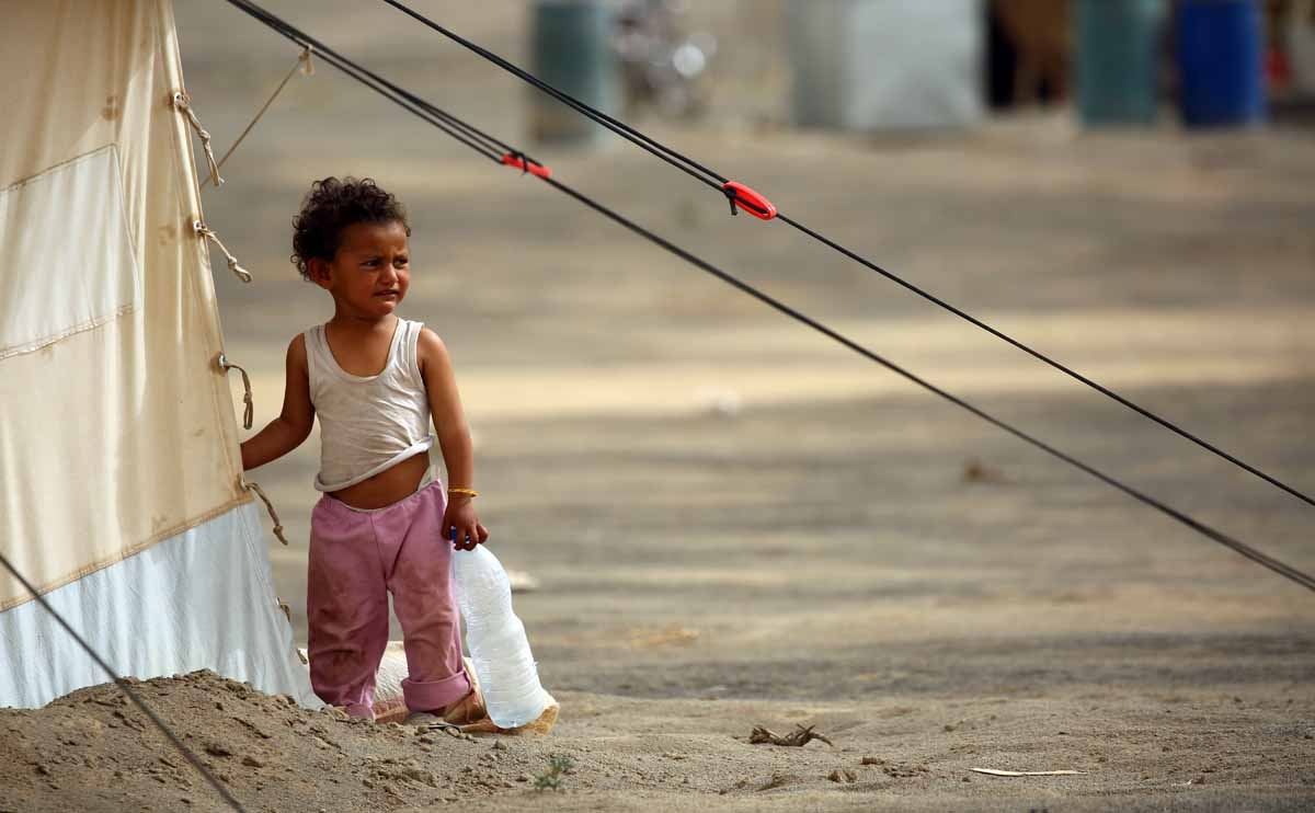 A displaced child, who fled from the Islamic State (IS) group bastion of Raqa, holds a plastic bottle outside a tent in a camp for displaced near the town of al-Karamah, 26 kms from Raqa, on May 10, 2017.