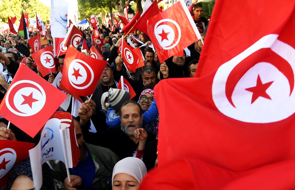 Tunisians wave their national flag as they gather on Habib Bourguiba Avenue in Tunis on January 14, 2018 to mark the seven year anniversary since the uprising that launched the Arab Spring. A wave of peaceful protests and night-time unrest hit cities and