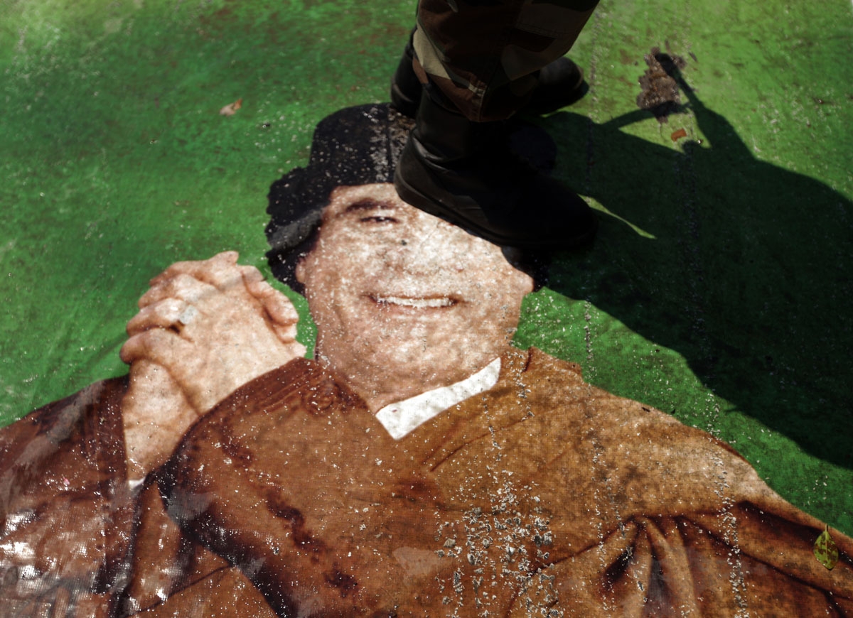 A Libyan rebel stands on a picture of Libyan leader Moamer Kadhafi in the rebel stronghold of Benghazi on June 22, 2011 as NATO defended the credibility of its air war in Libya after a bomb misfired killing civilians in Tripoli.