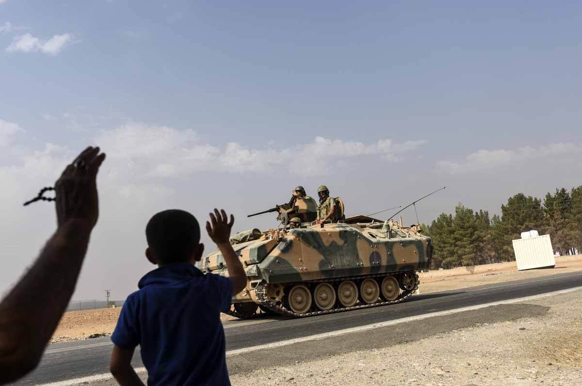 A Turkish boy waves to Turkish tank convoy driving into Syria from the Turkish Syrian border city of Karkamis in the southern region of Gaziantep, on August 26, 2016. A Turkish boy waves to Turkish tank convoy driving into Syria from the Turkish Syrian border city of Karkamis in the southern region of Gaziantep, on August 26, 2016.
