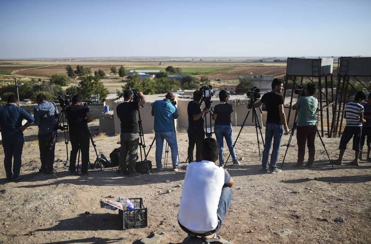 A man stands behind Turkish meida member working during clashes between Turkish army and ISIS on September 4, in at Elbeyli, in the southern region of Kilis. A man stands behind Turkish meida member working during clashes between Turkish army and ISIS on September 4, in at Elbeyli, in the southern region of Kilis.