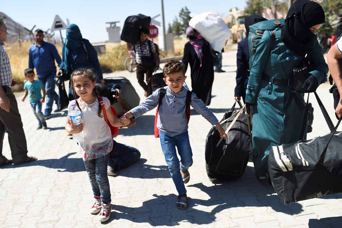 Syrian refugees walk on their way back to the Syrian city of Jarabulus on September 7, 2016 at Karkamis crossing gate, in the southern region of Kilis. Syrian refugees walk on their way back to the Syrian city of Jarabulus on September 7, 2016 at Karkamis crossing gate, in the southern region of Kilis.