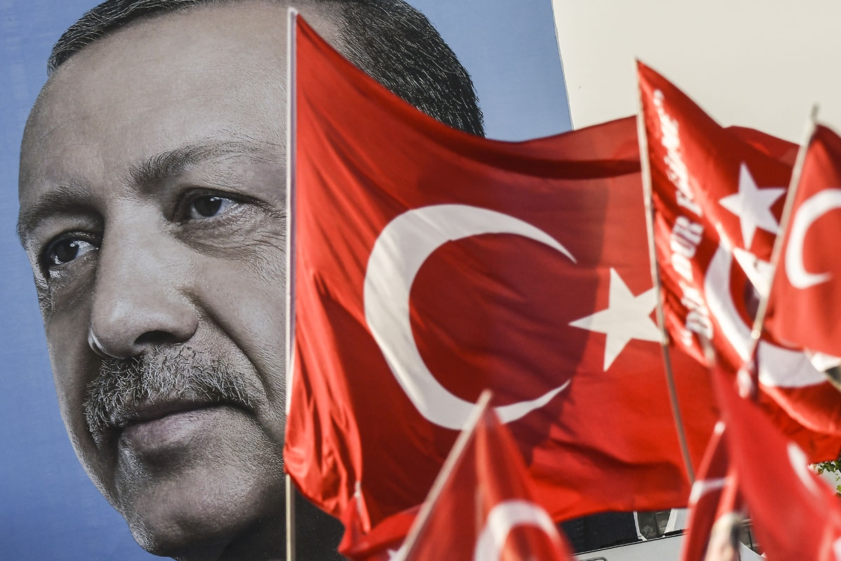 Turkish flags flutter nest to a huge portrait of Turkey's President and leader of the Justice and Development Party (AKP) Recep Tayyip Erdogan as he gives a speech during an AKP pre-election rally in Yenikapi Square in Istanbul on June 17, 2018.