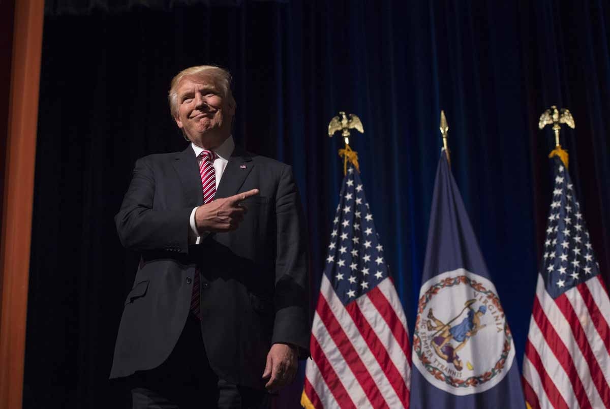 Republican presidential nominee Donald Trump listens while his son Eric Trump speaks during a campaign event at Briar Woods High School August 2, 2016, in Ashburn, Virginia. / AFP PHOTO / MOLLY RILEY