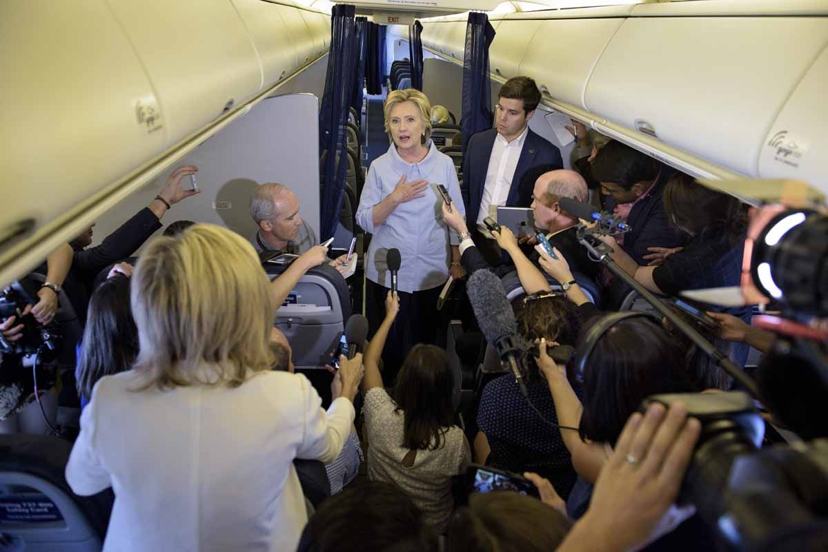 Democratic presidential nominee Hillary Clinton speaks to the press onboard her plane September 5, 2016 above Iowa. / AFP PHOTO / Brendan Smialowski