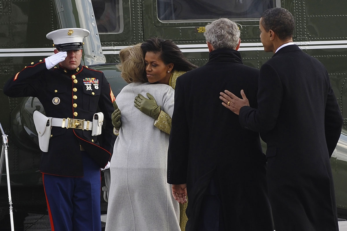 US President Barack Obama and former US President George W. Bush watch as First Lady Michelle Obama hugs former First Lady Laura Bush as the Bush's prepare to depart the US Capitol in Marine One after Obama was sworn in as the 44th US president in Washing