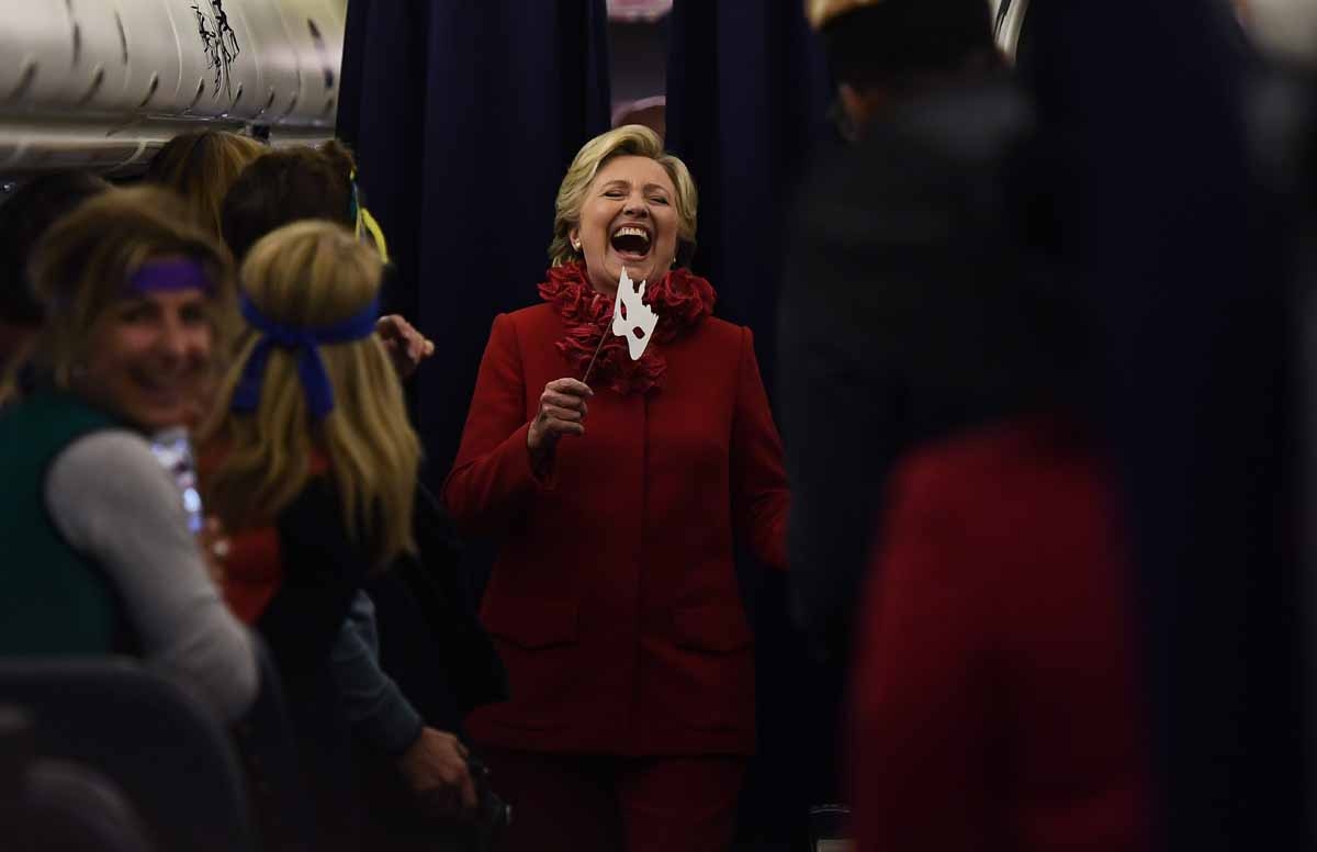 US Democratic presidential nominee Hillary Clinton smiles holding a mask onboard her campaign plane Erlanger, Kentucky, on October 31, 2016. US Democratic presidential nominee Hillary Clinton smiles holding a mask onboard her campaign plane Erlanger, Kentucky, on October 31, 2016.