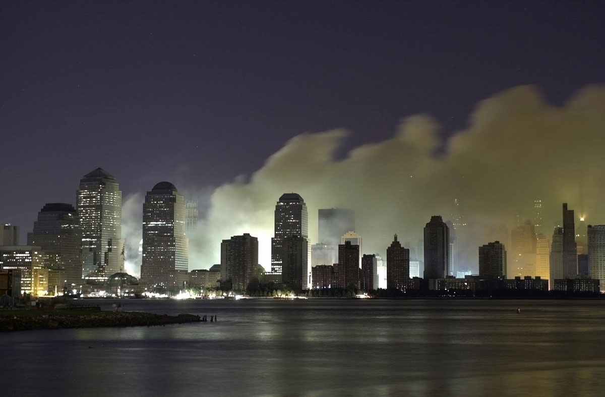Smoke and ash from the destroyed World Trade Center billows over the southern end of New York City's Manhattan as seen from Jersey City, New Jersey in the early morning, 12 September, 2001