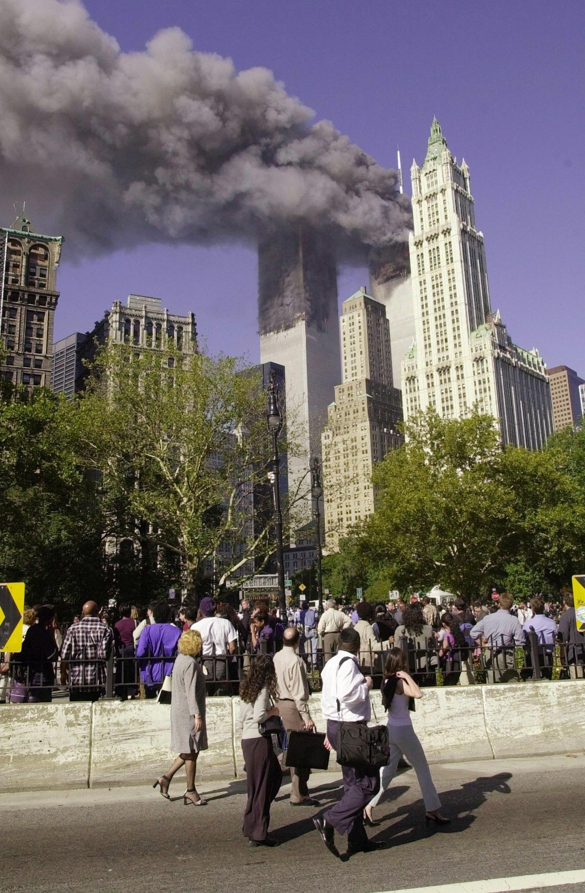 This file photo taken on September 11, 2001 shows pedestrians walking off the Brooklyn Bridge watching as smoke billows from the World Trade Center after two planes crashed into the towers in New York