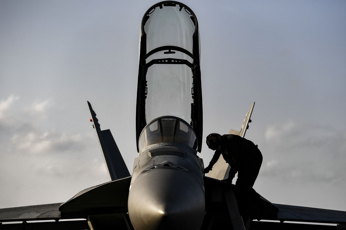 A crew member stands on the body of a F18 Hornet fighter jet on the deck of the US navy aircraft carrier USS Harry S. Truman in the eastern Mediterranean Sea on May 8, 2018.