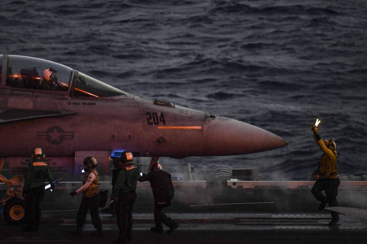 A crew member of the 330 meters US navy aircraft carrier Harry S. Truman gestures as a pilot of an F18 Hornet fighter jet waits to take off on eastern Mediterranean Sea on May 8, 2018.