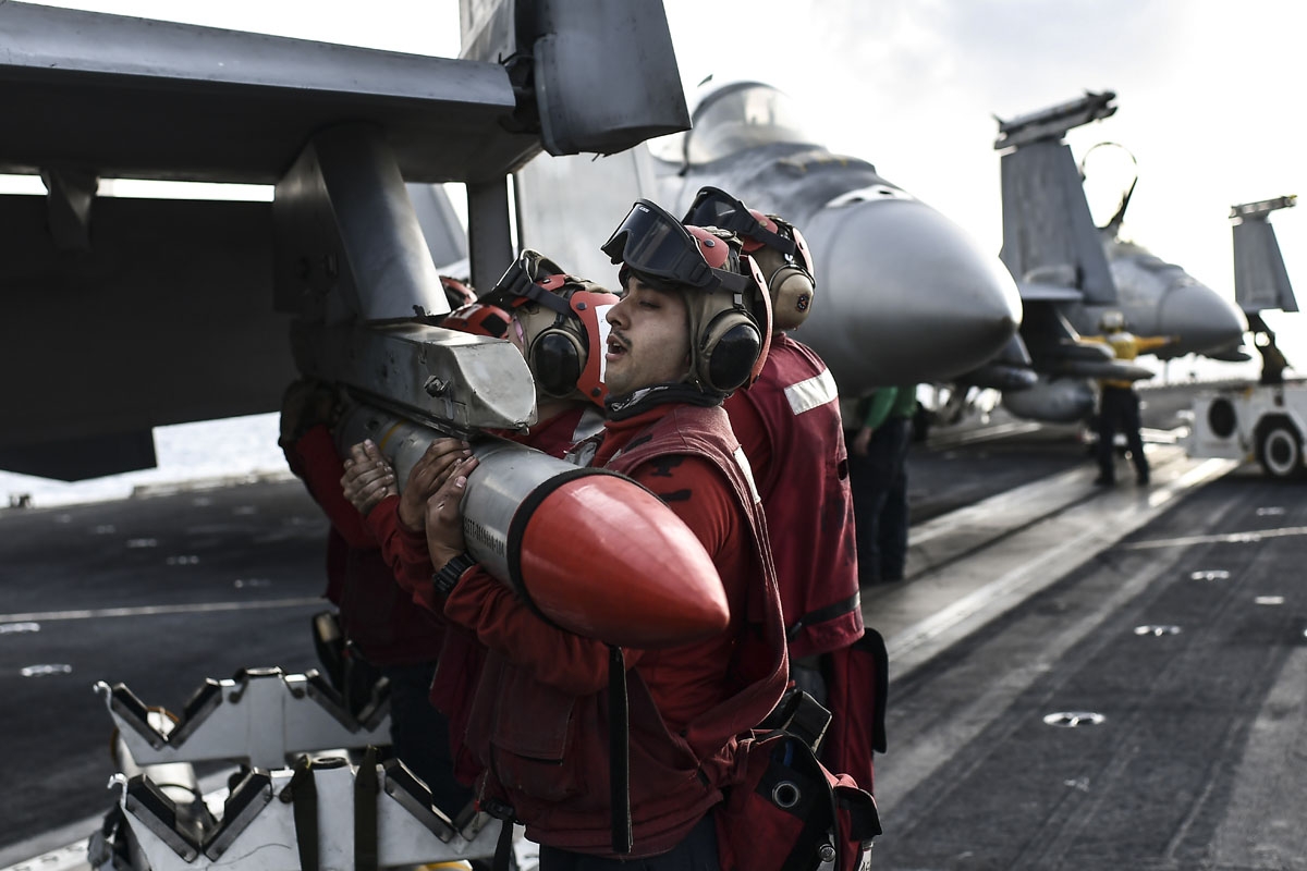 Crew members of US aircraft carrier USS Harry S Truman lift a missile into place on the wing of an F18 Hornet fighter jet on the flight deck of the ship in the eastern Mediterranean Sea on May 8, 2018.