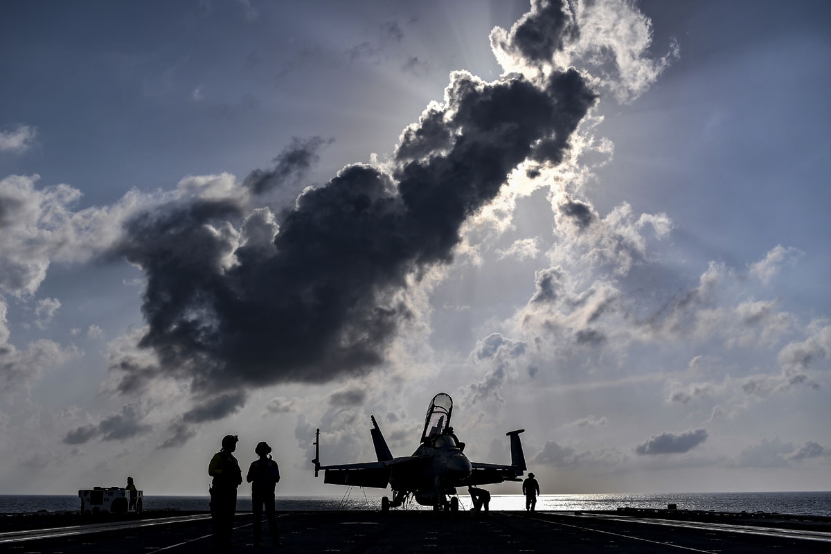 Crew members of US aircraft carrier USS Harry S Truman stand beside an F18 Hornet fighter jet on the flight deck of the ship in the eastern Mediterranean Sea on May 8, 2018.