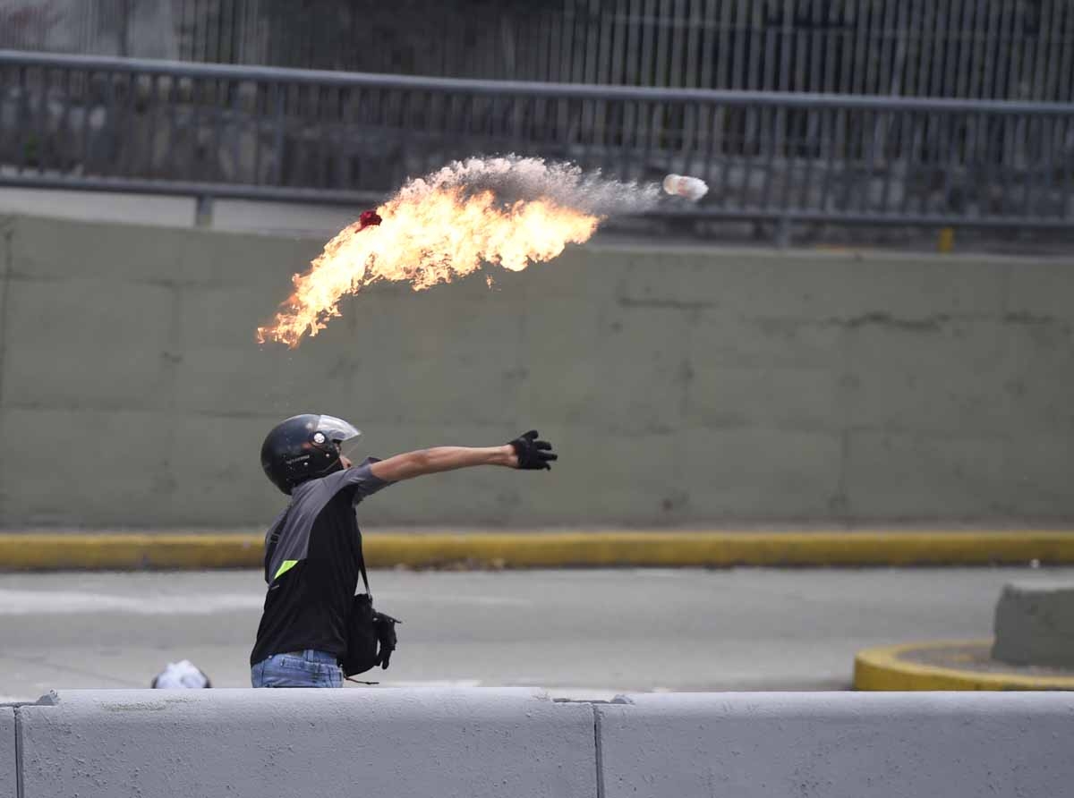 A demonstrator against Nicolas Maduro's government throws a Molotov cocktail during clashes with riot police at eastern Caracas on April 8, 2017.