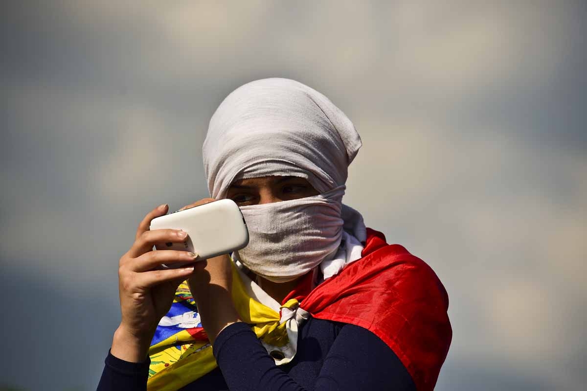 A masked Venezuelan opposition activist uses her cell-phone during a demonstration against Venezuelan President Nicolas Maduro in Caracas, on April 24, 2017.