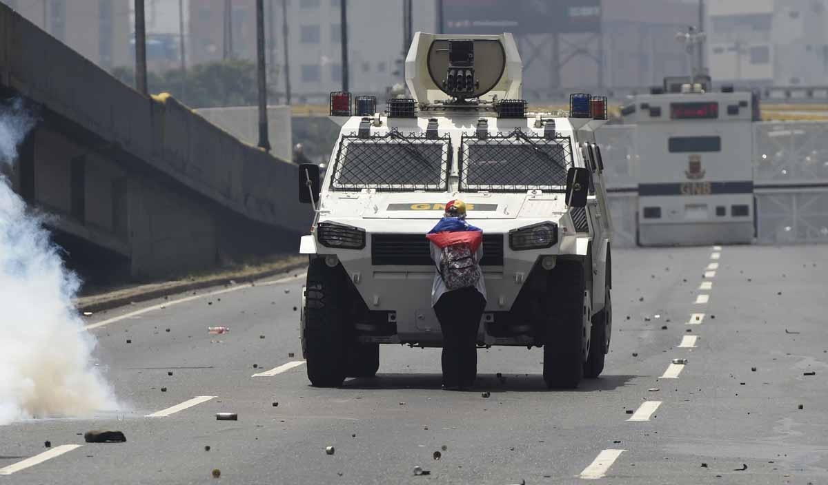 A demonstrator stands in front of an armoured vehicle of the riot police during a rally against Venezuelan President Nicolas Maduro, in Caracas on April 19, 2017. Clashes broke out Wednesday at massive protests against Maduro, as riot police fired tear ga