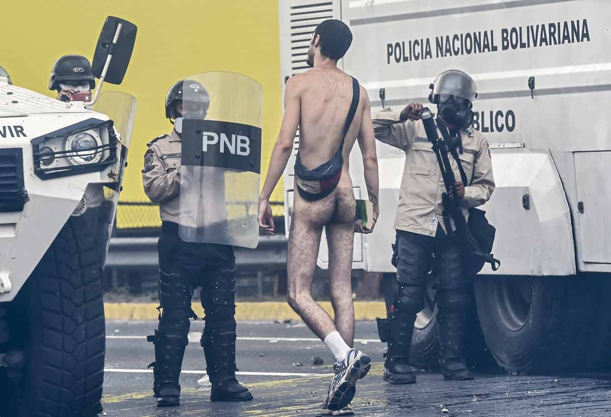 A naked demonstrator remonstrates with riot police during a protest against Venezuelan President Nicolas Maduro, in Caracas on April 20, 2017.