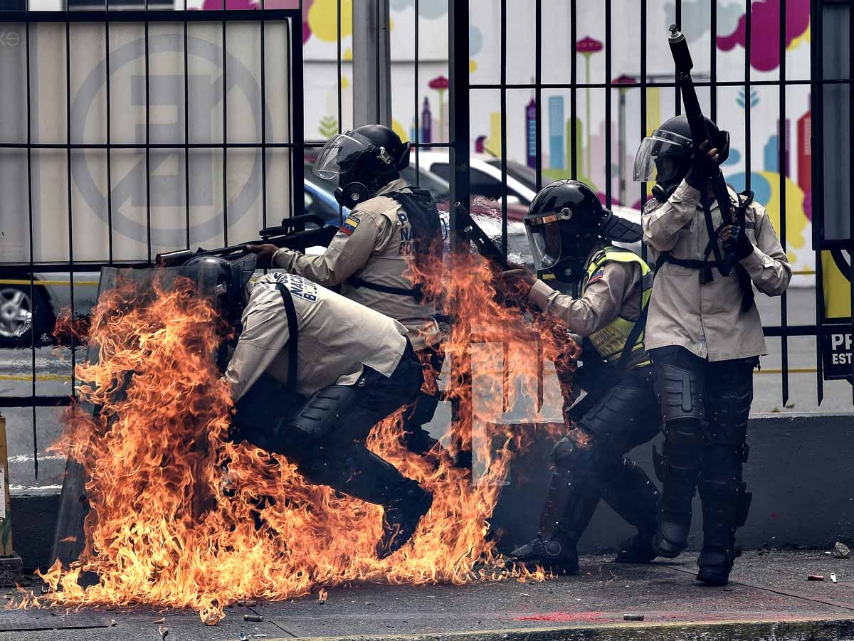A group of riot policemen are hit by a Molotov cocktail hurled by an opposition demonstrator during a protest against President Nicolas Maduro, in Caracas on May 8, 2017.